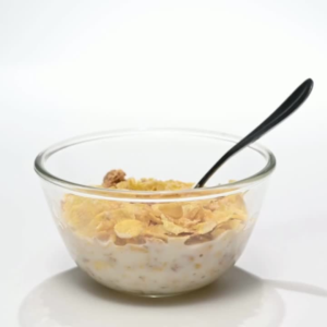 Glass bowl of whole grain cereal with milk and a spoon, a fiber-rich breakfast option for the microbiome diet