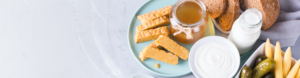 Best probiotics for skin and gut: tempeh, yogurt, honey, whole grain bread, milk, and pickles arranged on a table